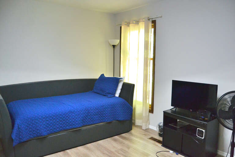 Your comfortable room features a cozy daybed, natural light, and entertainment setup to help you unwind after exploring the area.