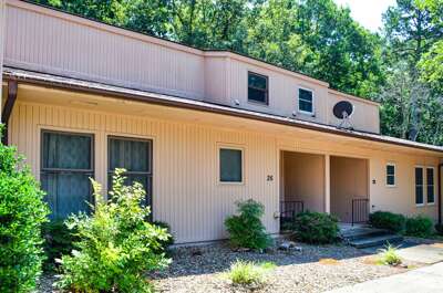 Modern two-story property nestled in a peaceful wooded setting, featuring multiple units and convenient parking access.
