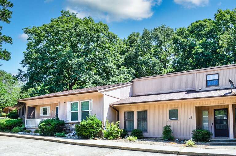 A modern townhouse-style vacation rental nestled among lush mature trees, offering a peaceful retreat with convenient parking and private entrance.