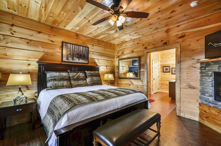 Bedroom with a large bed, twin nightstands, and fireplace with TV above.