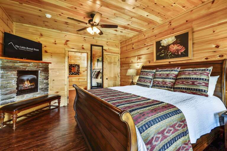 Large bed in a bedroom with a large TV and fireplace by the foot of it.