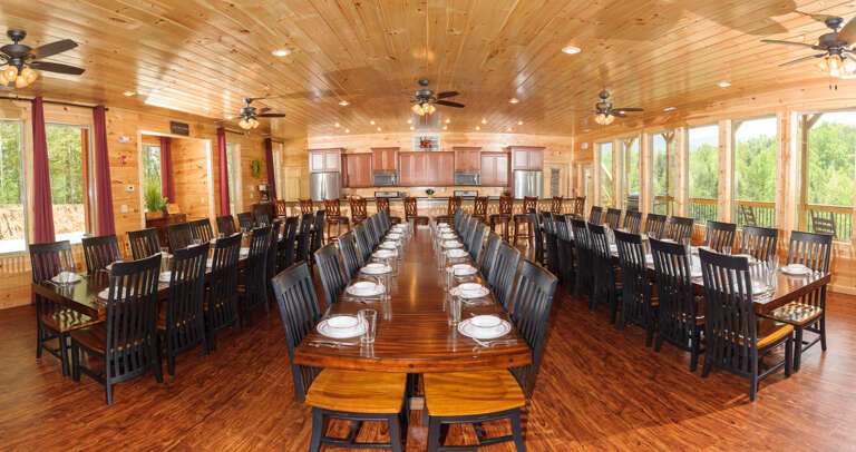 Massive dining area with three long dining tables and many, many chairs.