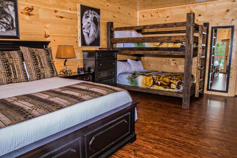 Bedroom with Large Bed, Bunk Bed, Dresser, Nightstands, Lamps, and Mirror.