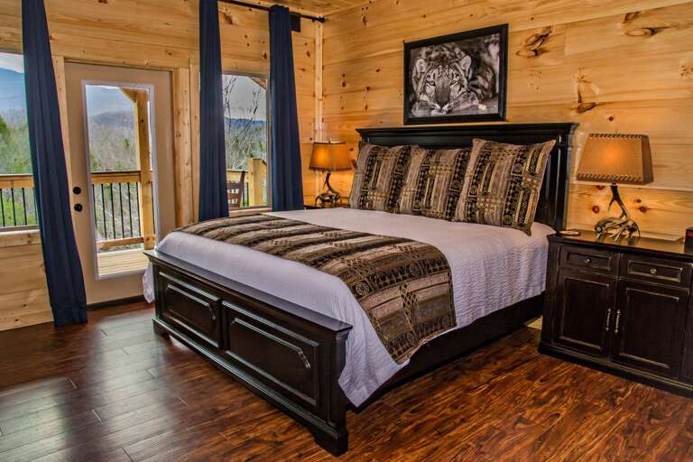 Bedroom with Large Bed, Dresser, Nightstands, Lamps, and Window Door to the Balcony.
