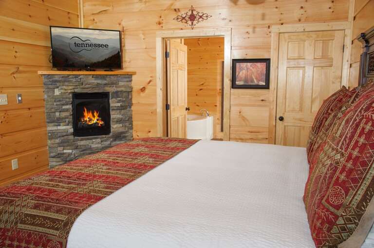 Bedroom with Large Bed, Fireplace, TV, and Bathtub.