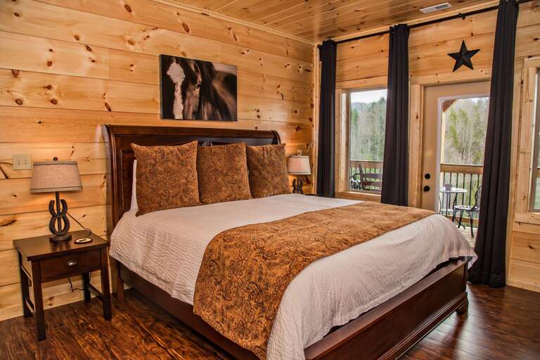 Bedroom with Large Bed, Nightstands, Lamps, Windows, and Door to the Balcony.