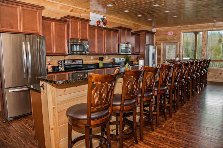 Kitchen with Breakfast Bar, Stools, Two Refrigerators, Two Microwaves, and Two Stoves.