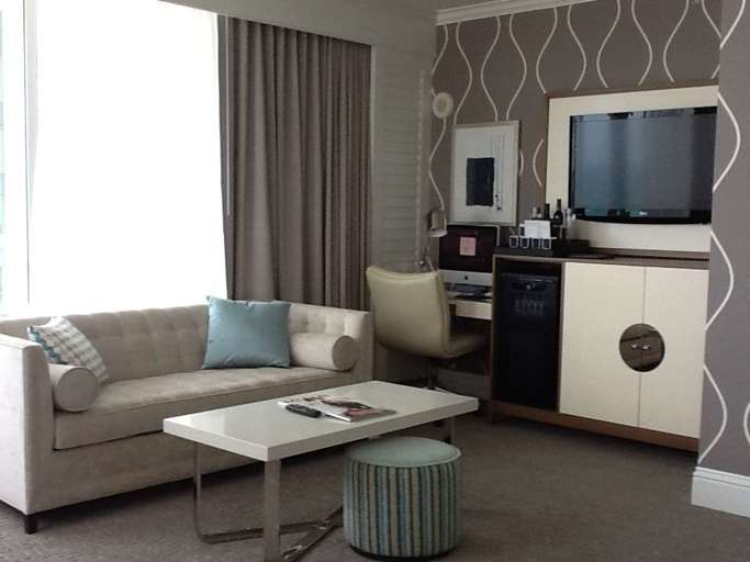 Modern Living Room With Beige Sofa, Patterned Wallpaper, And Office Desk