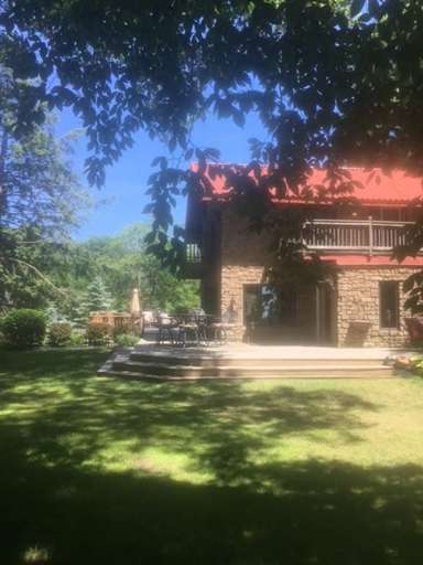 Stone House With Red Roof And Patio Under Tree Shade