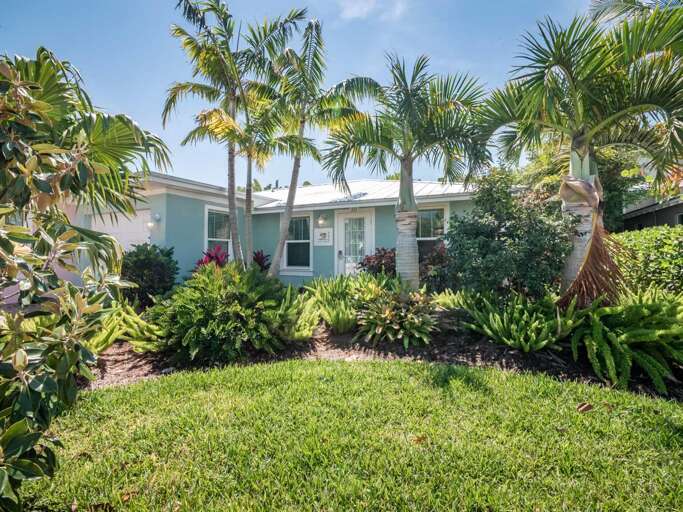 Palm-lined Property With Green Garden And Blue Building