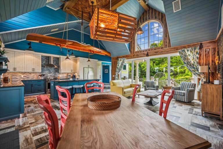 Spacious Blue-hued Room With Wooden Furnishings, Large Windows, And A Ceiling Kayak