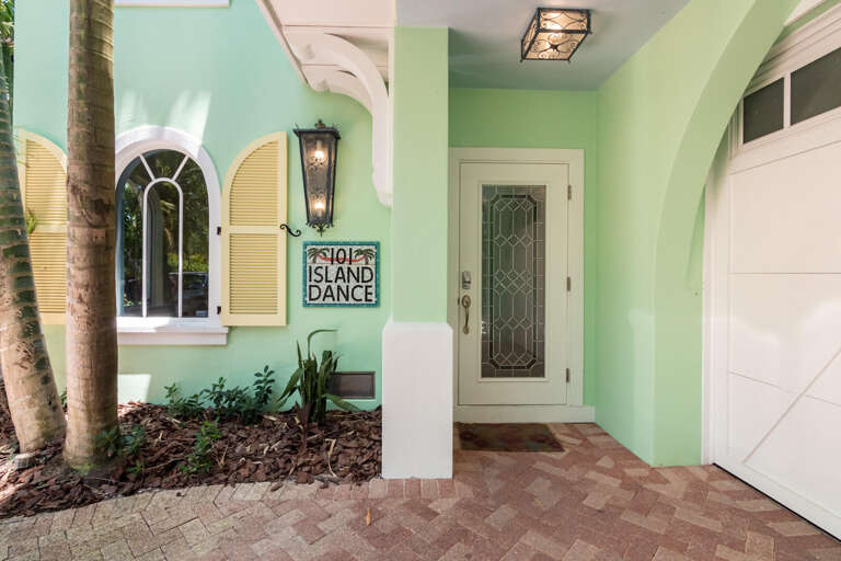 Palm-bordered Pathway Leading To The Pastel-painted Entrance Of A Serene Structure