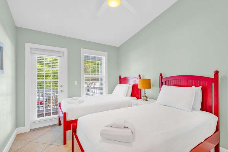 Bright twin bedroom in a Marathon FL canal-front vacation home offering modern décor, comfortable sleeping space, and easy access to pool and living areas.