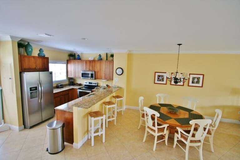 Open-concept dining area with seating for six, seamlessly integrated with a fully equipped kitchen featuring bar stools.