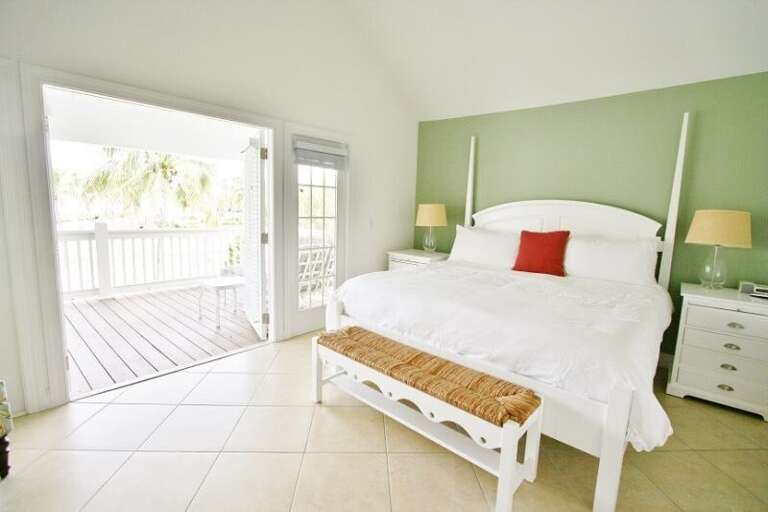 The master suite features a king bed, a large flat-screen television, and paned glass doors framing stunning open Gulf views.