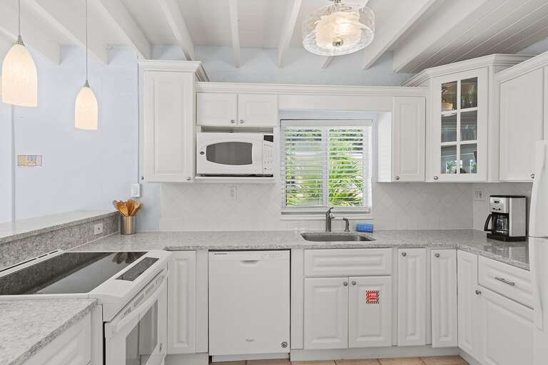 Full kitchen with bar stools, TV, and cozy nooka perfect space for cooking and casual dining.