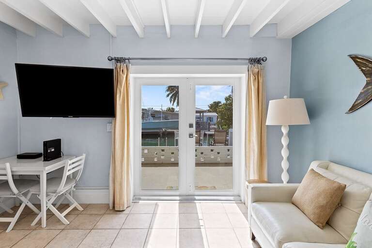 Living room flooded with natural light, framed by expansive glass doors, inviting the outdoors in.