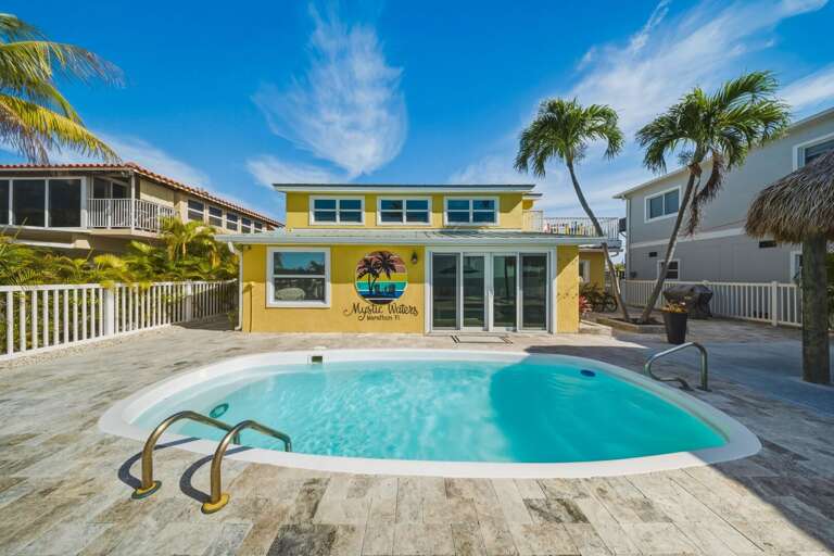 Private pool deck surrounded by lush tropical landscaping overlooking the ocean in the Florida Keys.