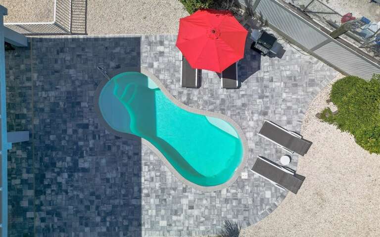 Pool deck with loungers, umbrella, & propane grill.