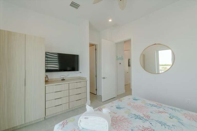 3rd level king bedroom with ensuite bathroom, smart TV, and access to balcony overlooking the pool and open water.