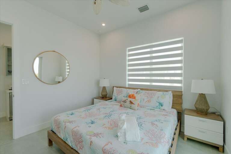 3rd level king bedroom with ensuite bathroom, smart TV, and access to balcony overlooking the pool and open water.