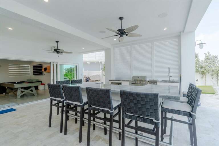 Full outdoor kitchen with gas grill, wet bar, and dining area.
