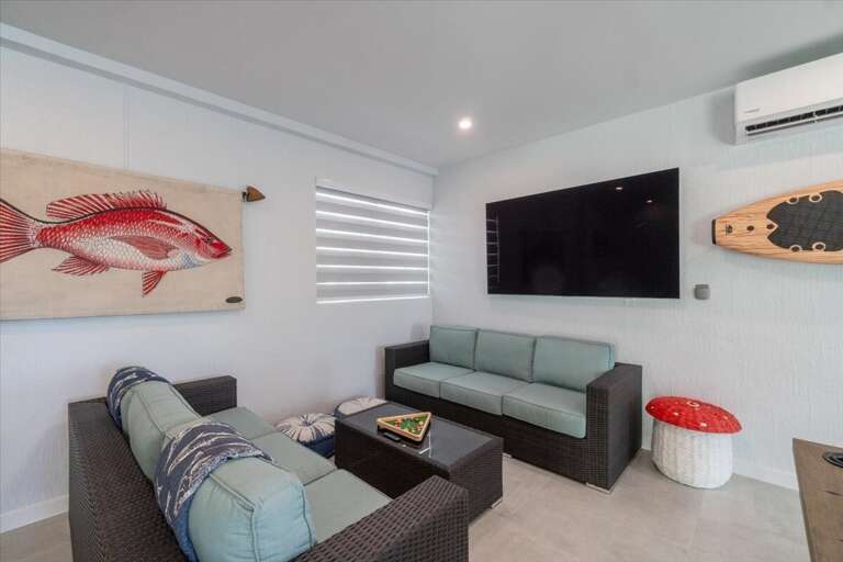 Indoor/outdoor entertainment room with pool table, dominos table, and TV.