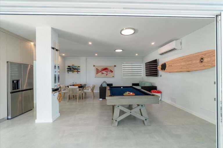 Indoor/outdoor entertainment room with pool table, dominos table, and TV.