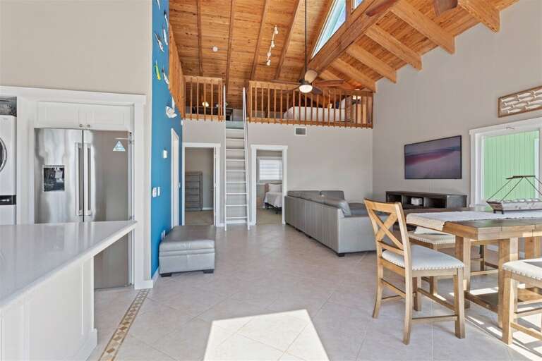 Airy elegance: Open-concept living, kitchen, and dining area beneath soaring ceilings. Airy elegance: Open-concept living, kitchen, and dining area beneath soaring ceilings.