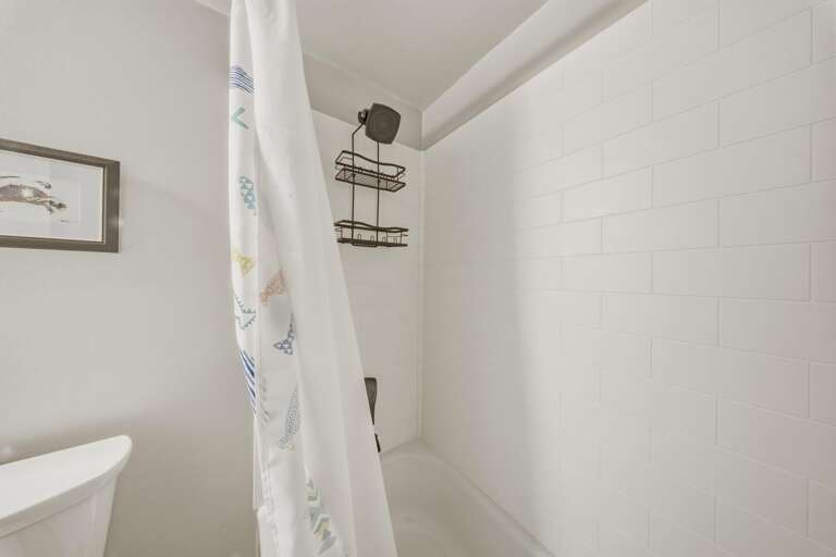 Bright white tile surrounds the tub and shower, creating a clean and refreshing space to begin or end your day.