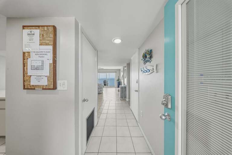 A cheerful aqua front door, beach-inspired artwork, and light tile flooring create a welcoming first impression as you enter this bright waterfront retreat.