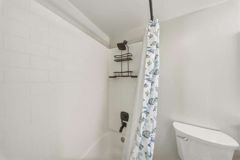 Clean white tile and a full tub and shower combination provide convenience for families, couples, and longer stays.