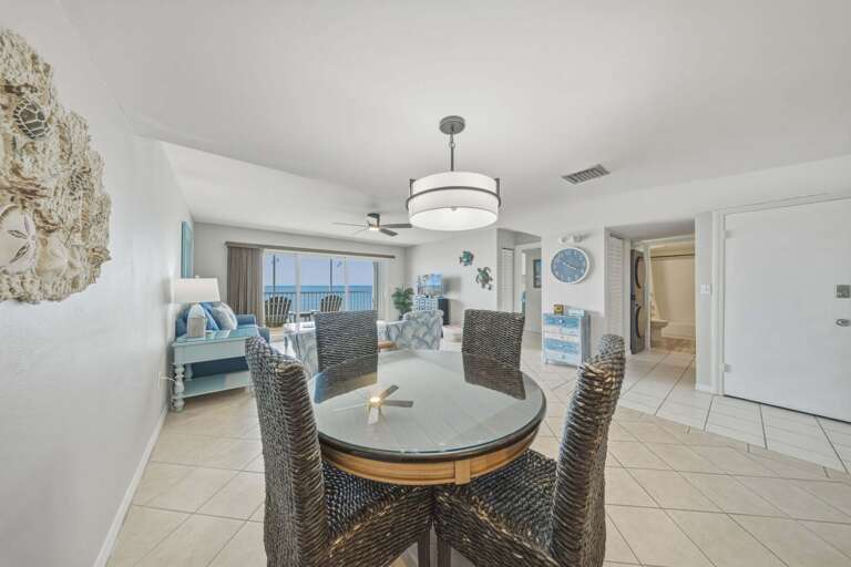 The round dining table and woven chairs provide an inviting place for meals, games, and conversations while enjoying views toward the living area.