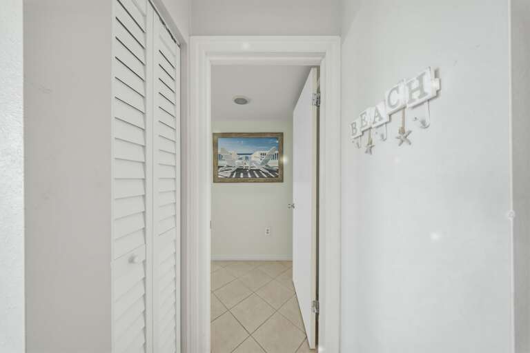 Beach-inspired artwork and bright finishes guide guests toward the private bedrooms and bathrooms tucked away from the main living area.