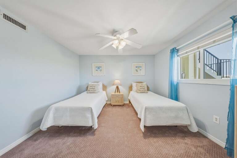 Soft blue walls, natural light, and comfortable twin beds create a relaxing bedroom designed for restful nights.