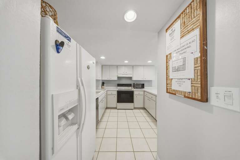 White cabinetry, full-size appliances, and generous workspace provide a bright and functional kitchen designed for easy meals and vacation living.