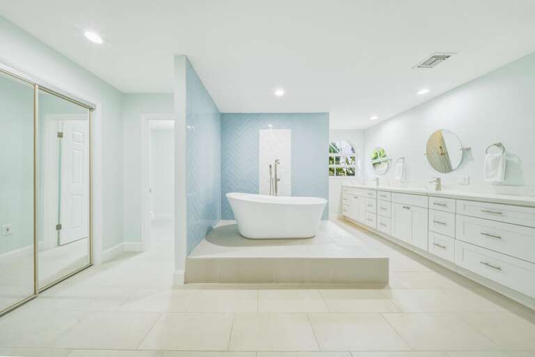 Relax in a spa-inspired primary bathroom featuring a freestanding soaking tub, designer finishes, and abundant natural light.