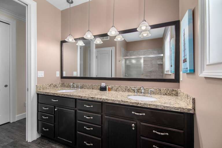 This well-appointed bathroom features dual sinks, generous storage, bright lighting, and a large wall mirror.