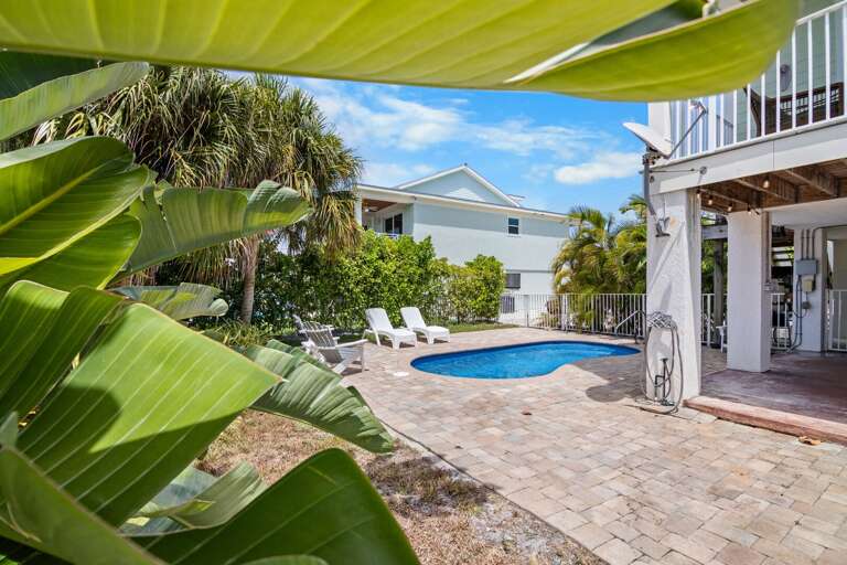 Lush landscaping surrounds the private pool and brick patio at this inviting Florida Keys vacation retreat.