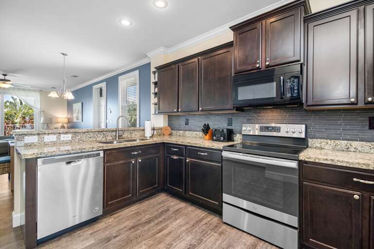 Prepare family meals in a well-equipped kitchen featuring dark cabinetry, stainless-steel appliances, and recessed lighting.