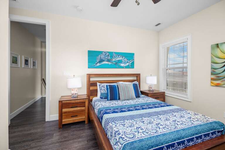 Recharge in a comfortable bedroom featuring blue island-inspired decor, warm wood furnishings, and natural light.