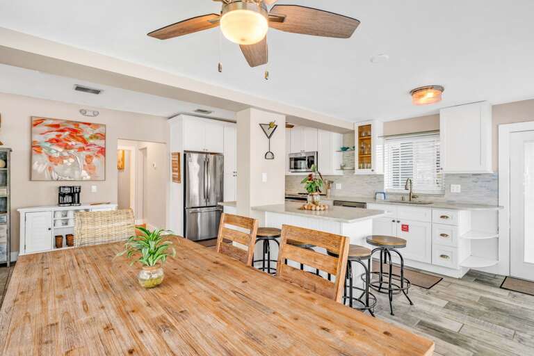 This open-concept kitchen flows seamlessly into the dining and living areas, with large windows framing ocean views for a relaxed and scenic culinary experience.
