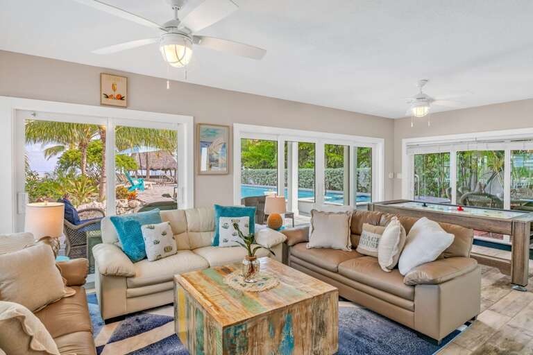 Relax in this spacious oceanfront living room featuring large windows that showcase stunning panoramic views of the Florida Keys, perfect for unwinding with family and friends.
