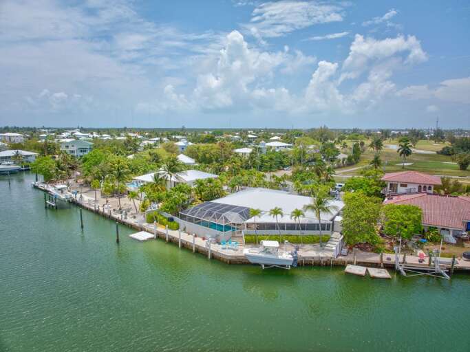 Bird's-eye view highlighting heated screened-in pool, hot tub, and outdoor kitchen at this Keys waterfront rental. Bird's-eye view highlighting heated screened-in pool, hot tub, and outdoor kitchen at this Keys waterfront rental.