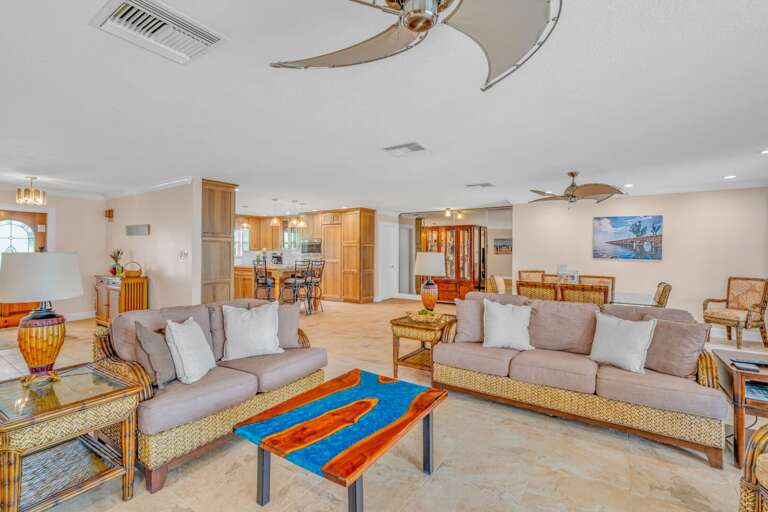 Luxury Florida Keys rental home living area with comfortable seating, large TV, and panoramic views of the pool and water. Luxury Florida Keys rental home living area with comfortable seating, large TV, and panoramic views of the pool and water.