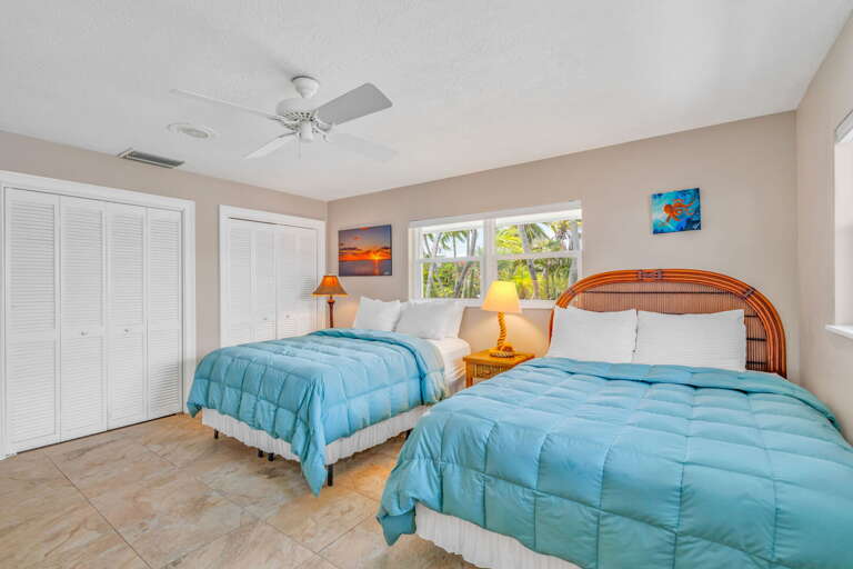 Spacious third bedroom featuring two queen beds, flat-screen TV, built-in speakers, and closet in a Florida Keys vacation rental. Spacious third bedroom featuring two queen beds, flat-screen TV, built-in speakers, and closet in a Florida Keys vacation rental.