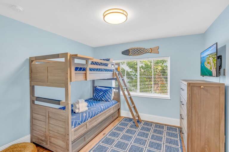 Ideal for kids or additional guests, this third-level bedroom features twin-over-twin bunk beds with a pull-out trundle, Smart TV, and coastal décor in Marathon FL.