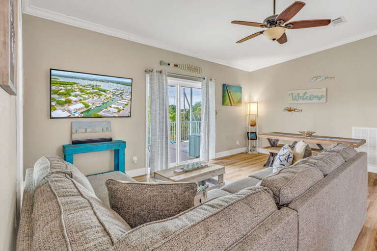 Bright and spacious open-plan living space featuring large windows overlooking the canal, perfect for relaxing with family or entertaining guests in the Florida Keys.
