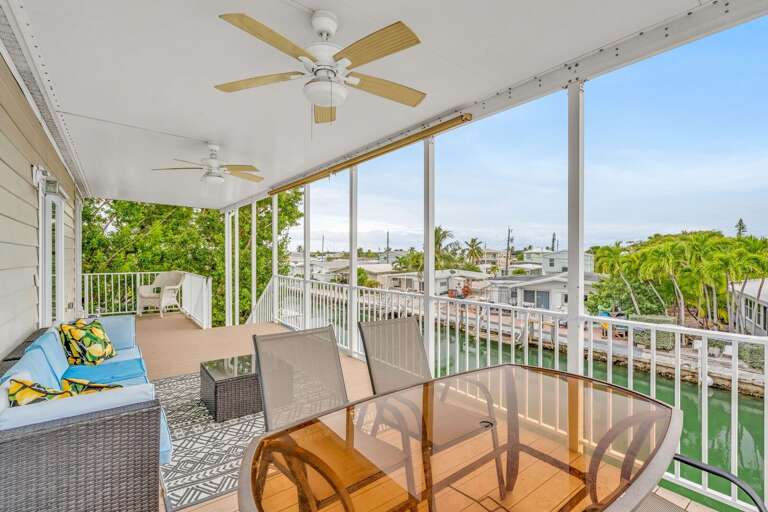 Enjoy breathtaking canal and water views from this spacious balcony, featuring a dining table and comfortable seating for relaxing or alfresco meals in the Florida Keys.