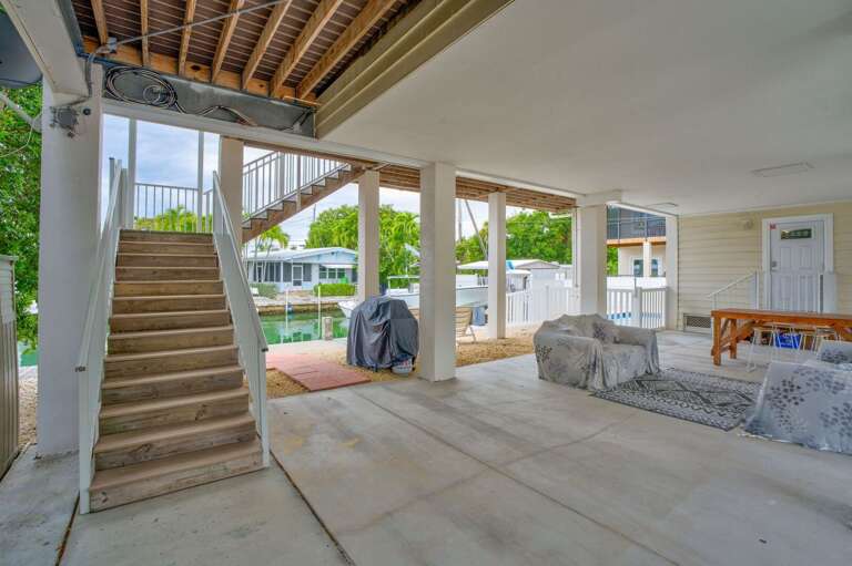 Enjoy shaded comfort and tropical breezes from this covered lanai, perfectly situated beside the private dock in a Florida Keys waterfront home.